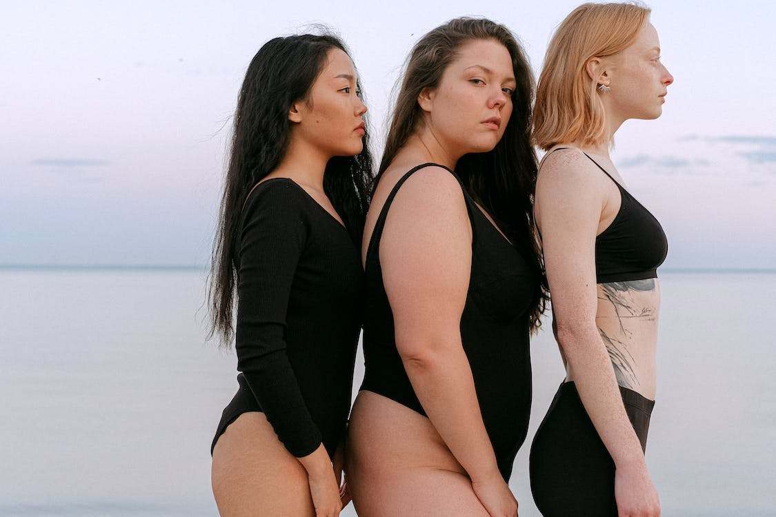 Three women of different body types, wearing black bathing suit