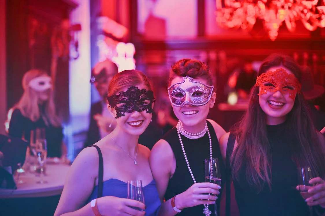 Three women wearing masquerade masks