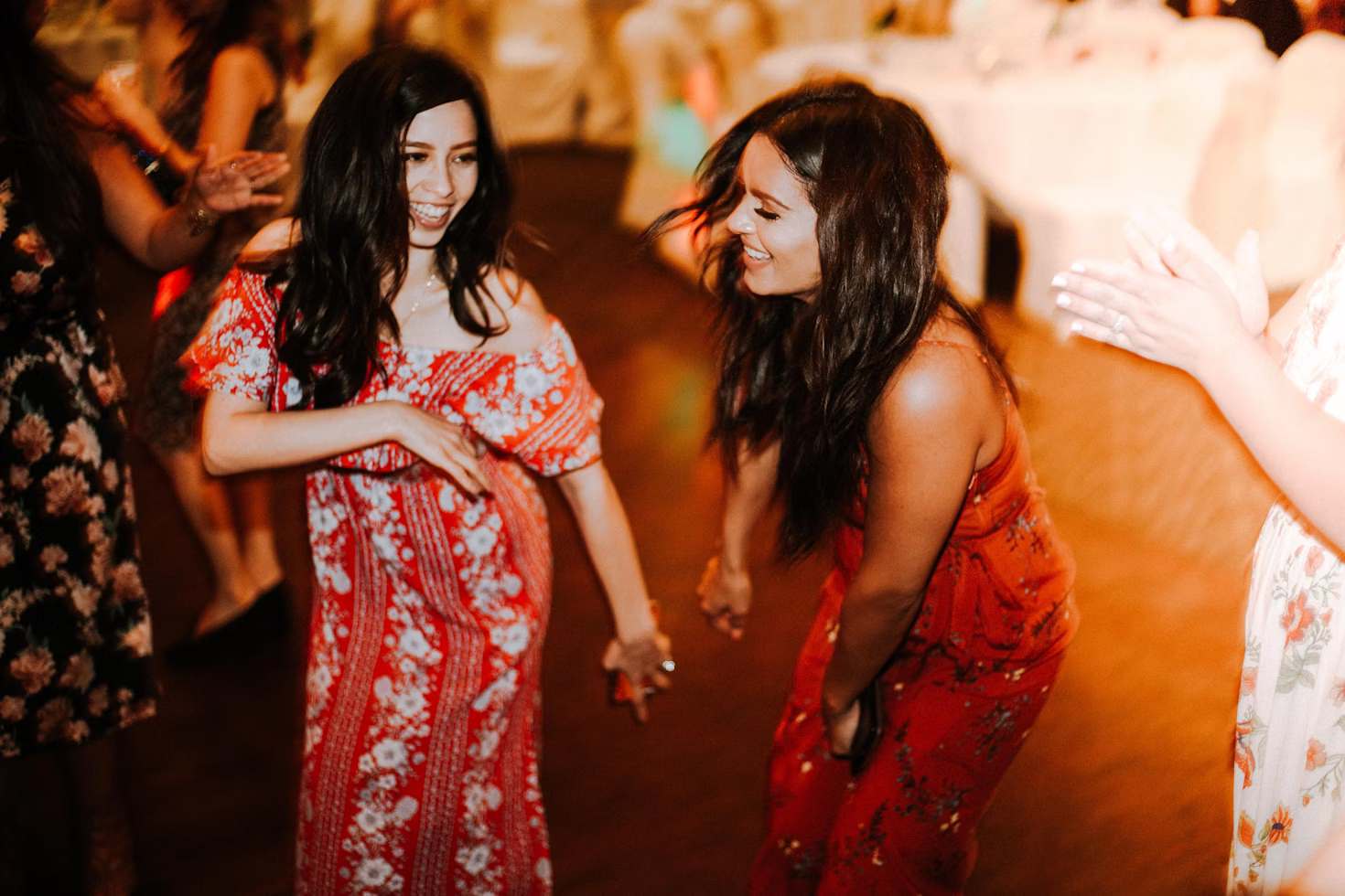 Two girls dancing and laughing, wearing both red toned dresses