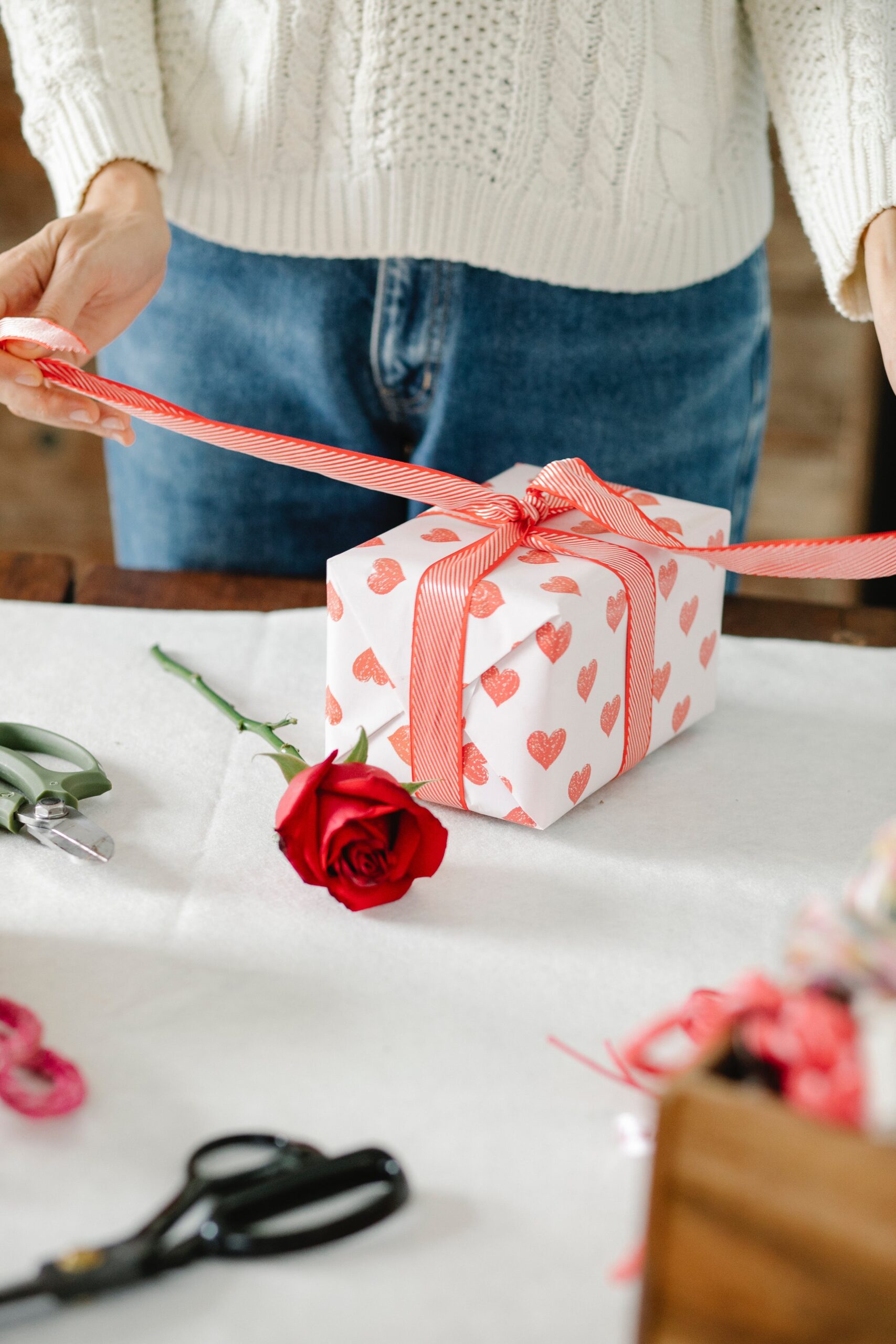 unrecognizable woman tying a bow on the present box on Saint Valentine's Day