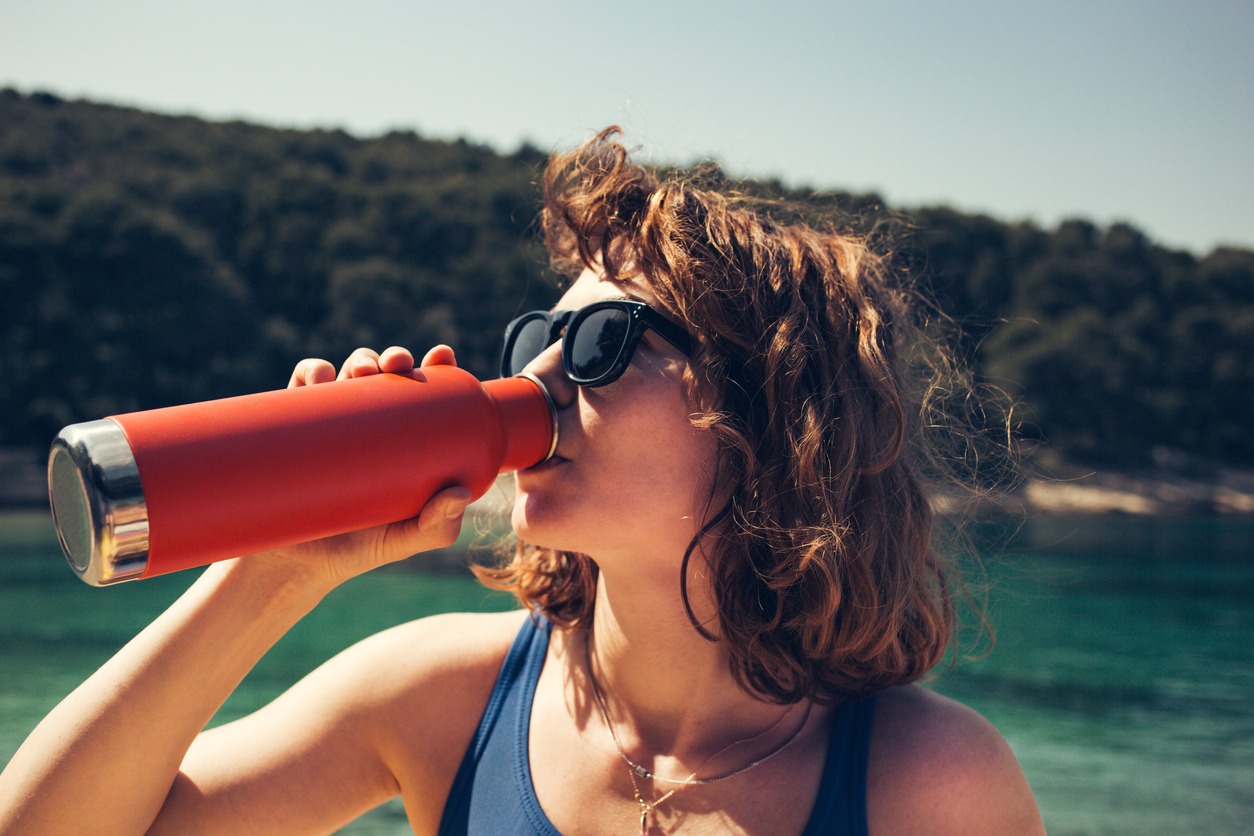 woman drinking from thermos bottle