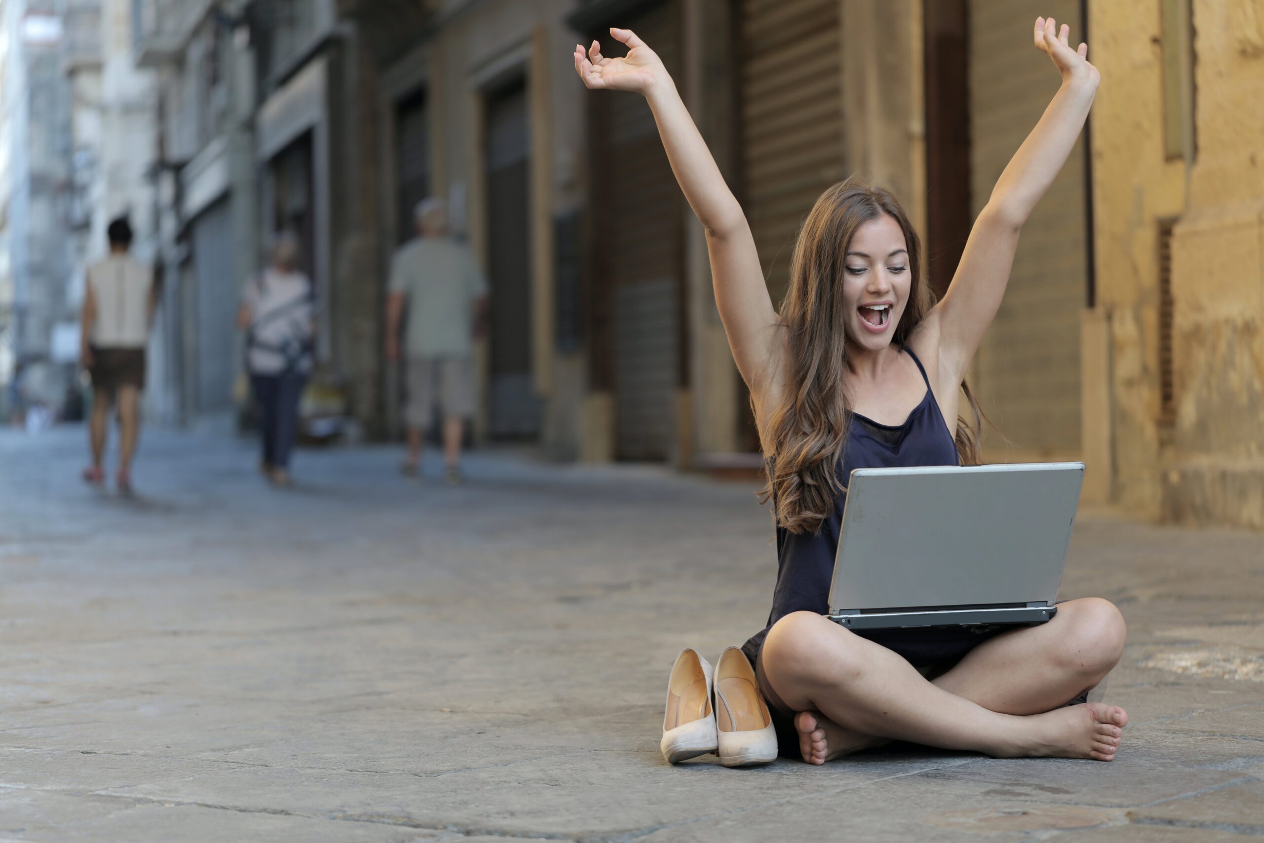 woman raising her hand while sitting on floor with MacBook Pro on lap