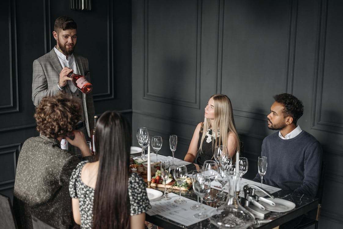 Man introducing a bottle of wine to a group of people