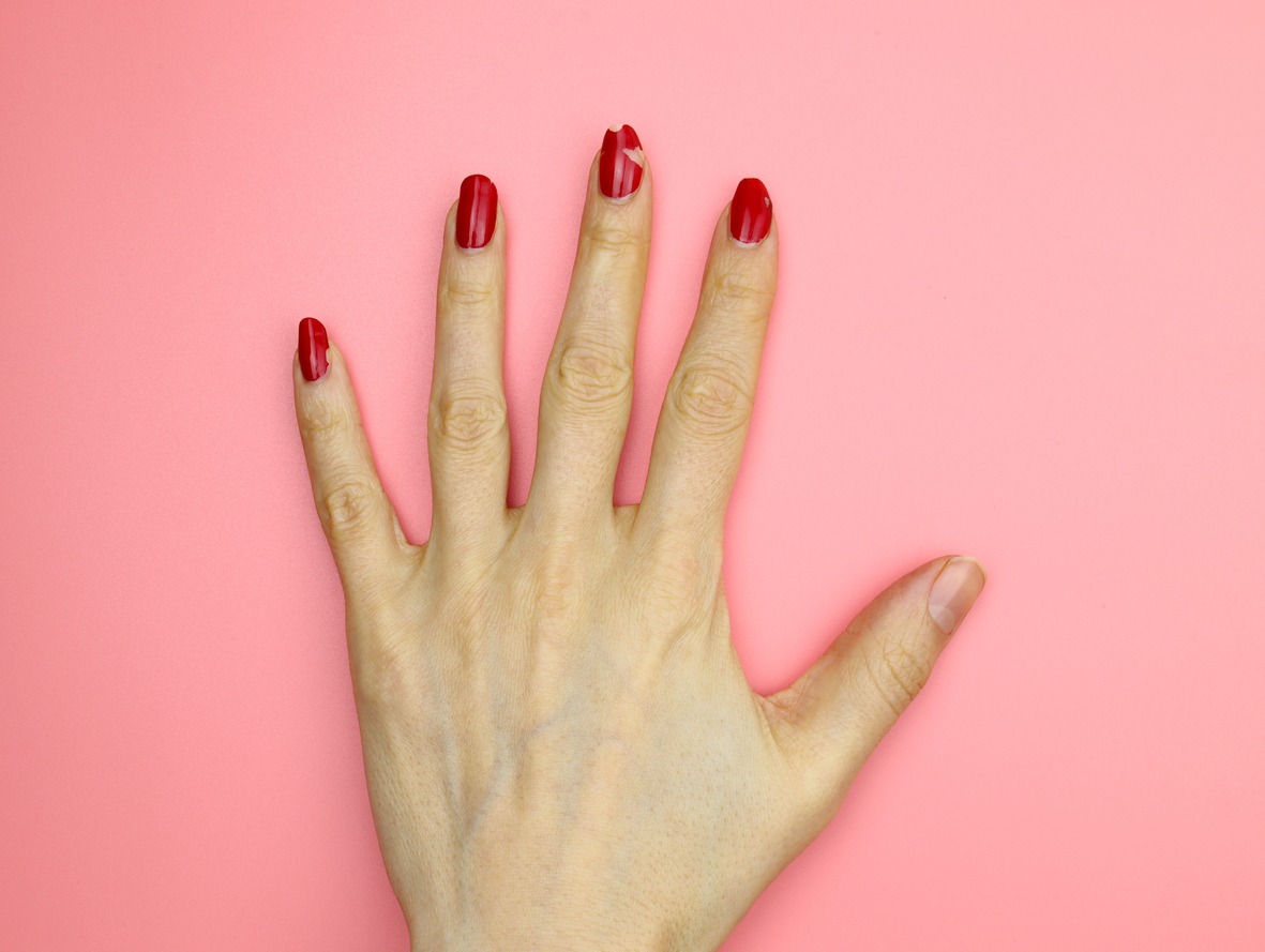 Girls hand with red nail polish without manicure